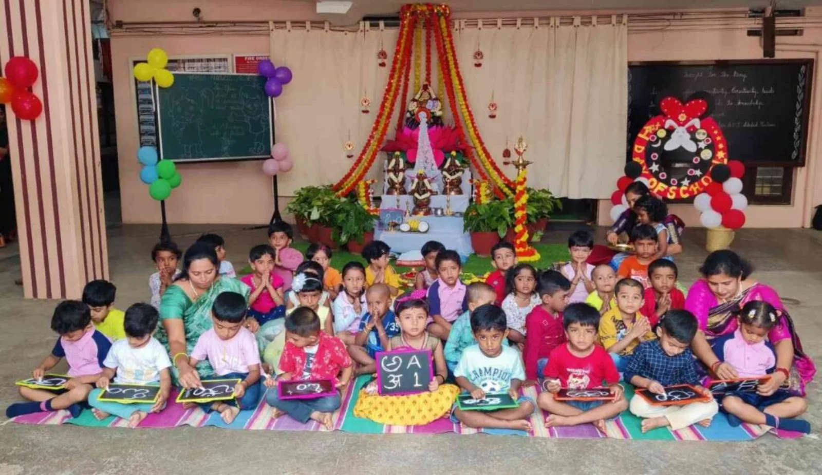 Small children sitting together on the floor for a festival celebration in a decorated corner of the classroom