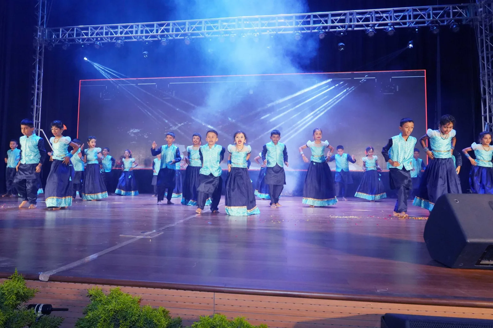 Students in colourful costume performing a group dance on the Annual Day stage