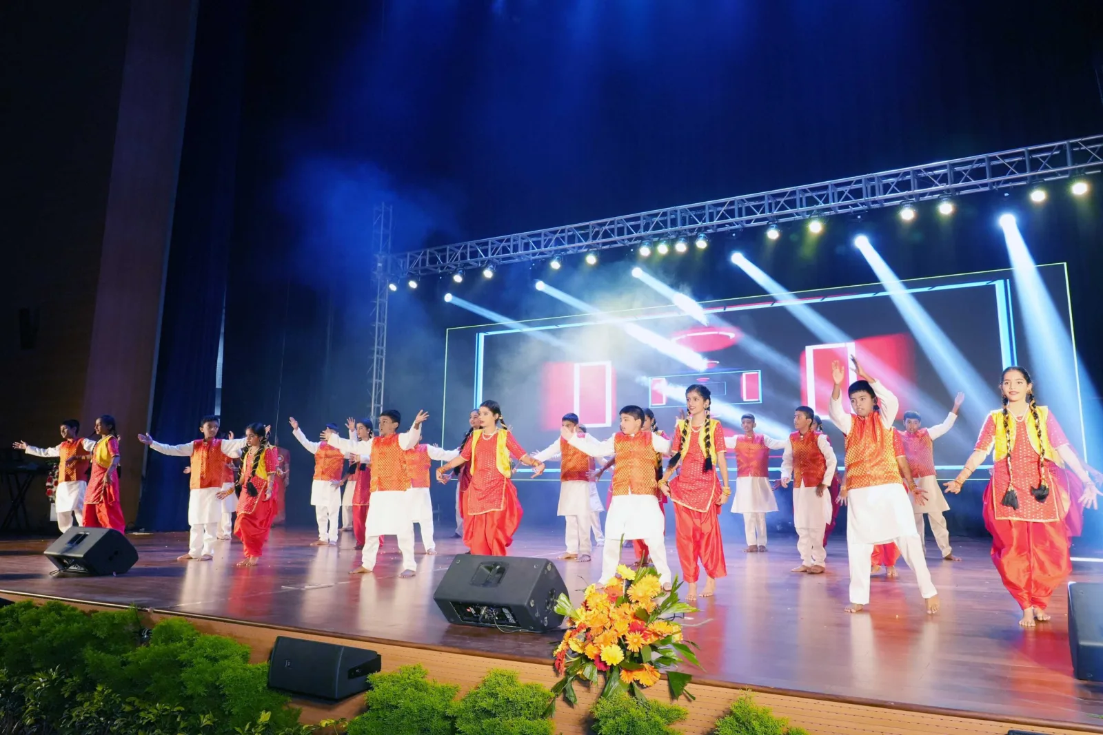 Students in green gowns performing a graceful dance on the Annual Day stage