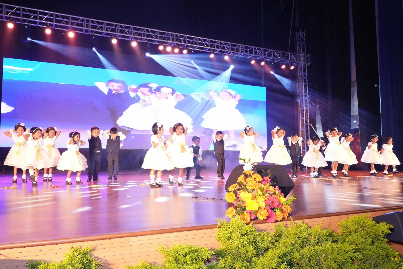 A choir of students in maroon costume performing on the Annual Day stage