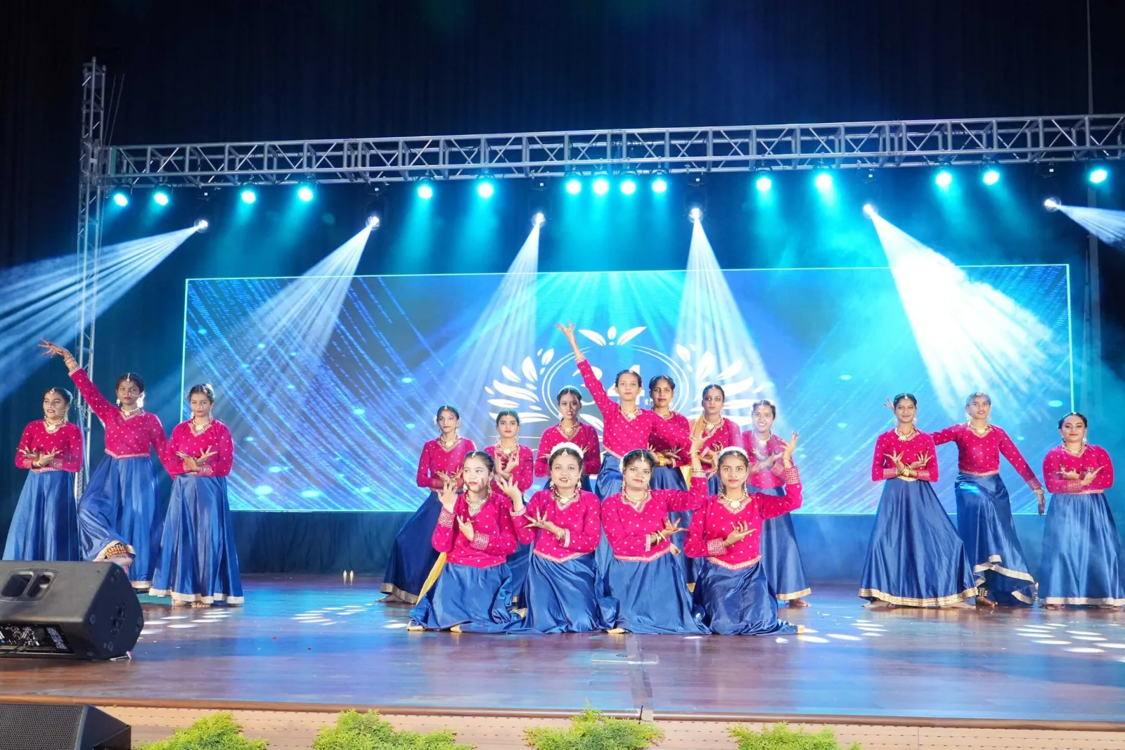 Students in yellow costume dancing in front of a floral stage backdrop