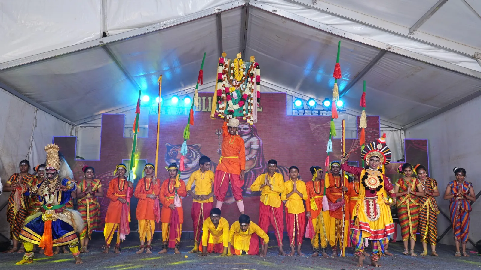 A large group of students in folk costume performing on a decorated outdoor stage