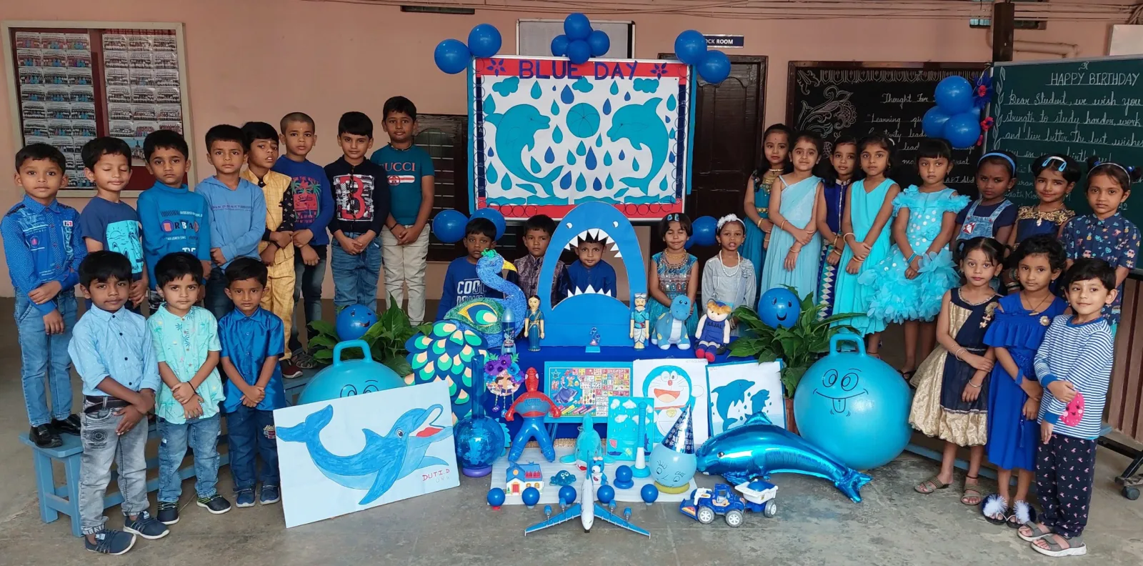 Young children dressed in blue for a themed celebration day, surrounded by blue decorations