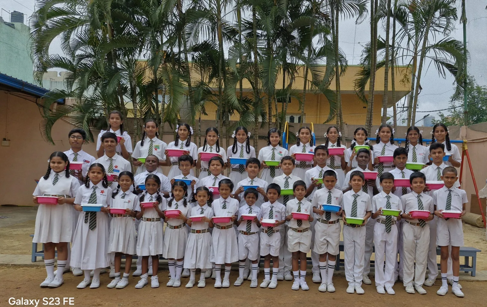A large group of students holding reusable lunch boxes given out in an eco-friendly drive
