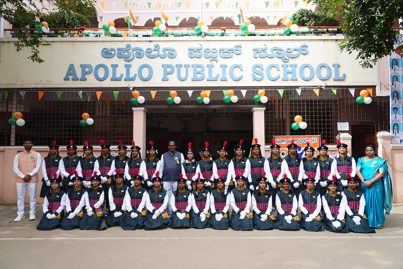 Students and staff posing together at the school gate, decorated for Independence Day