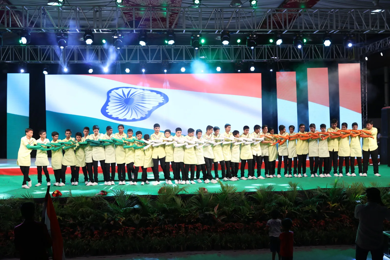 Students in tricolour costume performing a patriotic dance on stage