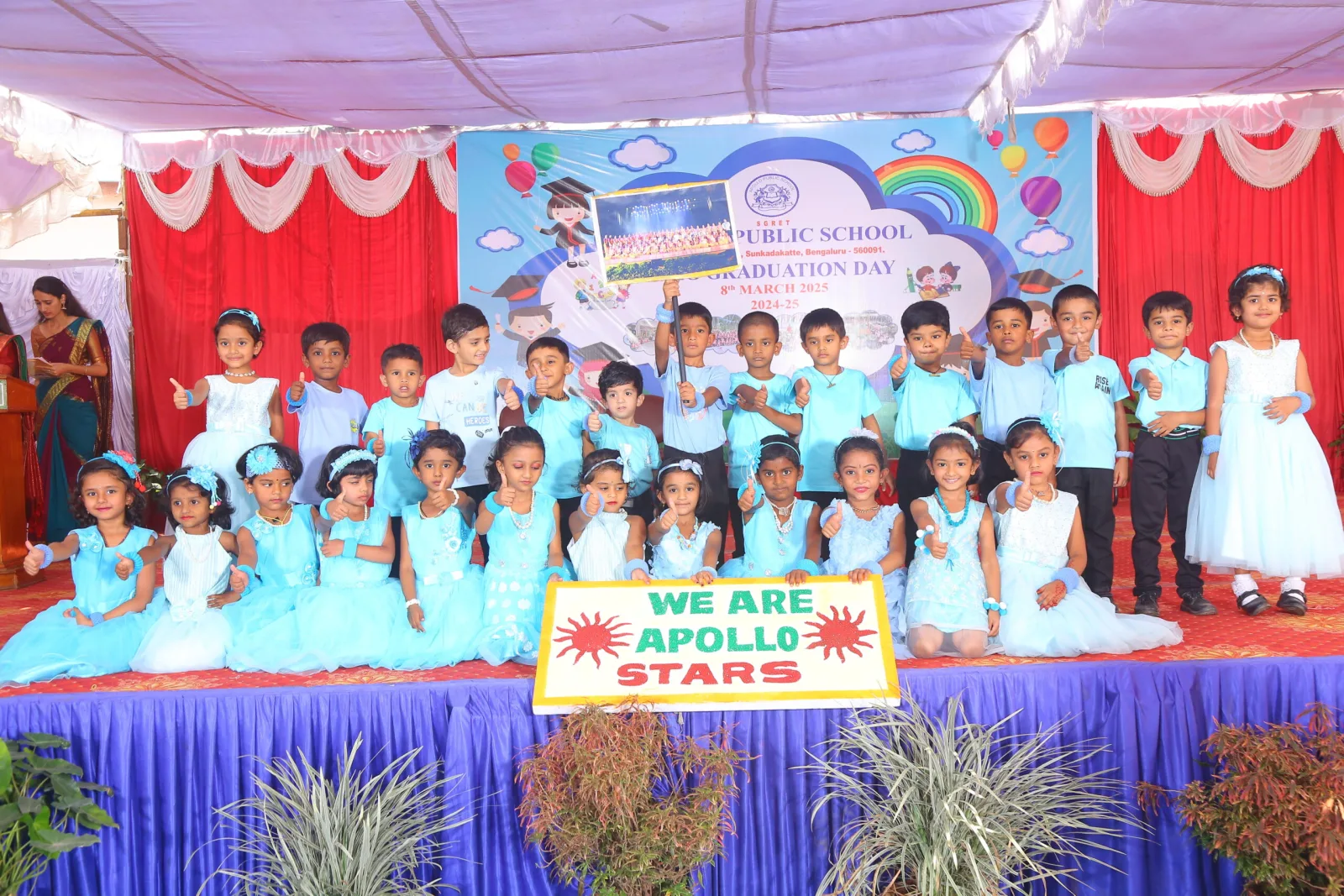 UKG children in matching blue outfits posing together on a decorated stage